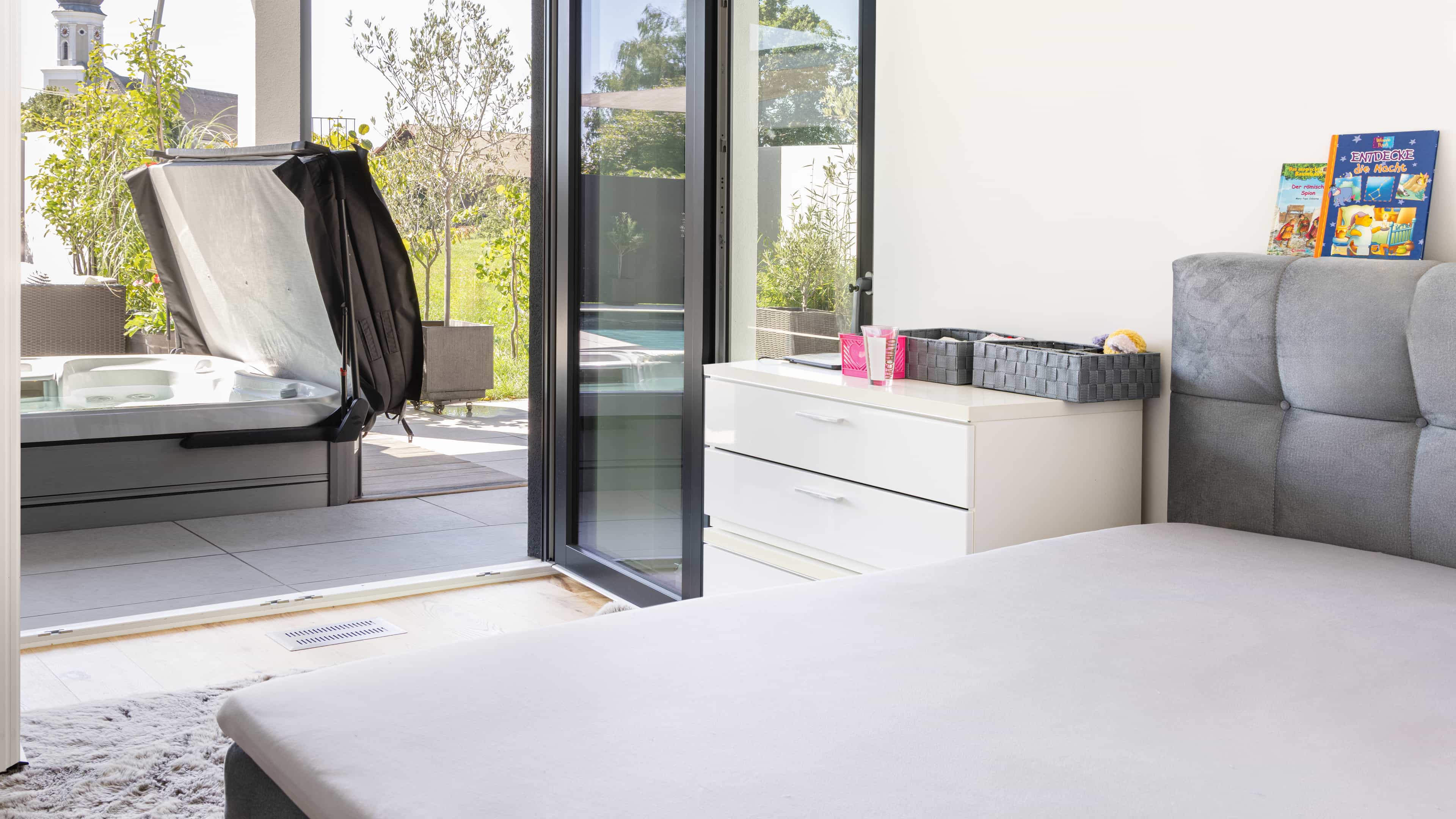 Schlafzimmer mit bodentiefer Schiebetür zur Poolterrasse im Bungalow der Familie Eder von Haas