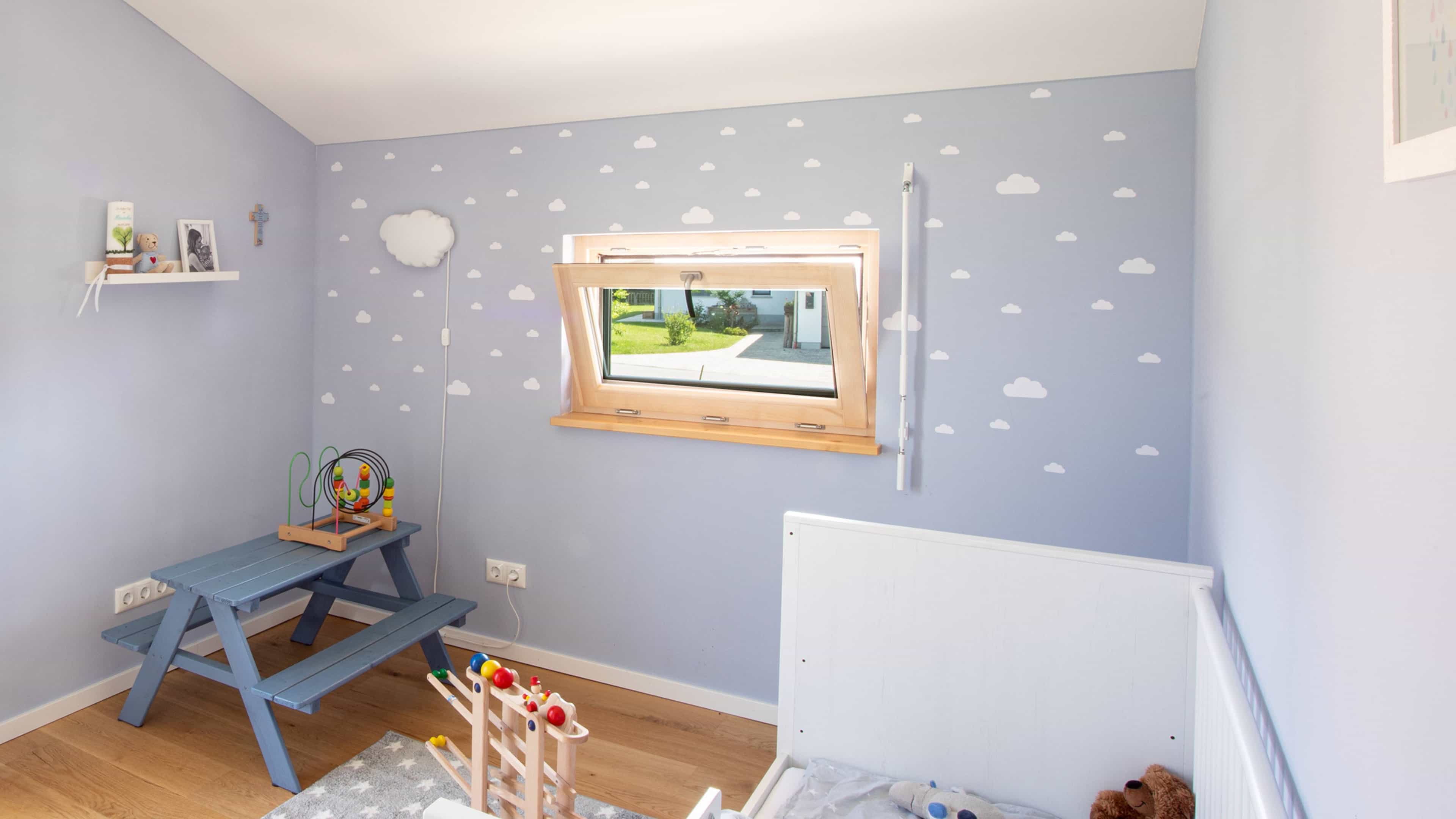 Kleines Kinderzimmer mit blauer Wand und Wolkenmuster, Holzfenster, Spielzeug und Minipicknicktisch.