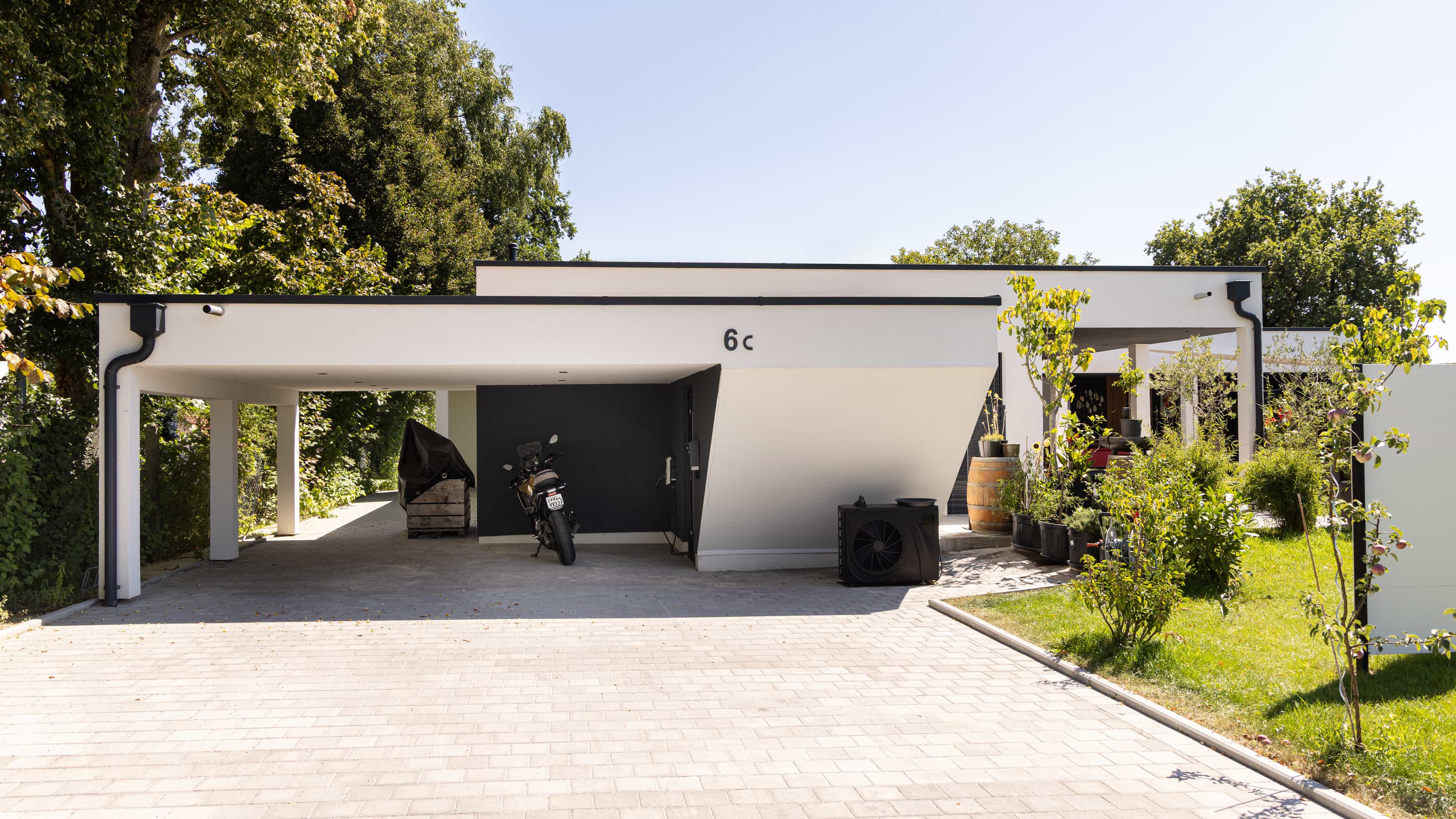 Carport mit Flachdach und gepflasterter Einfahrt am Bungalow der Familie Eder von Haas
