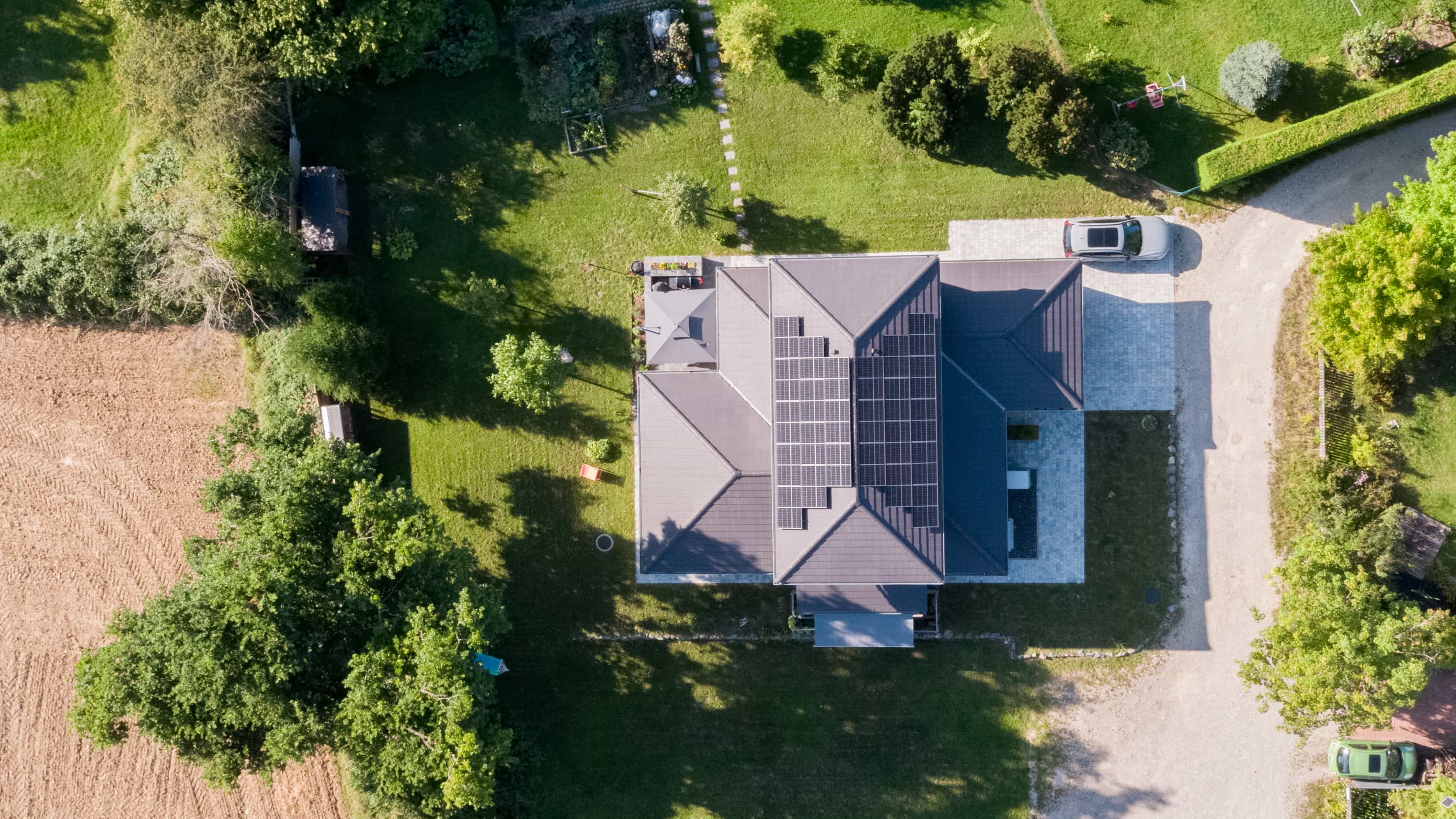 Luftaufnahme des Familienhauses Lampl mit Garten und Einfahrt inmitten von Wiesen und Feldern