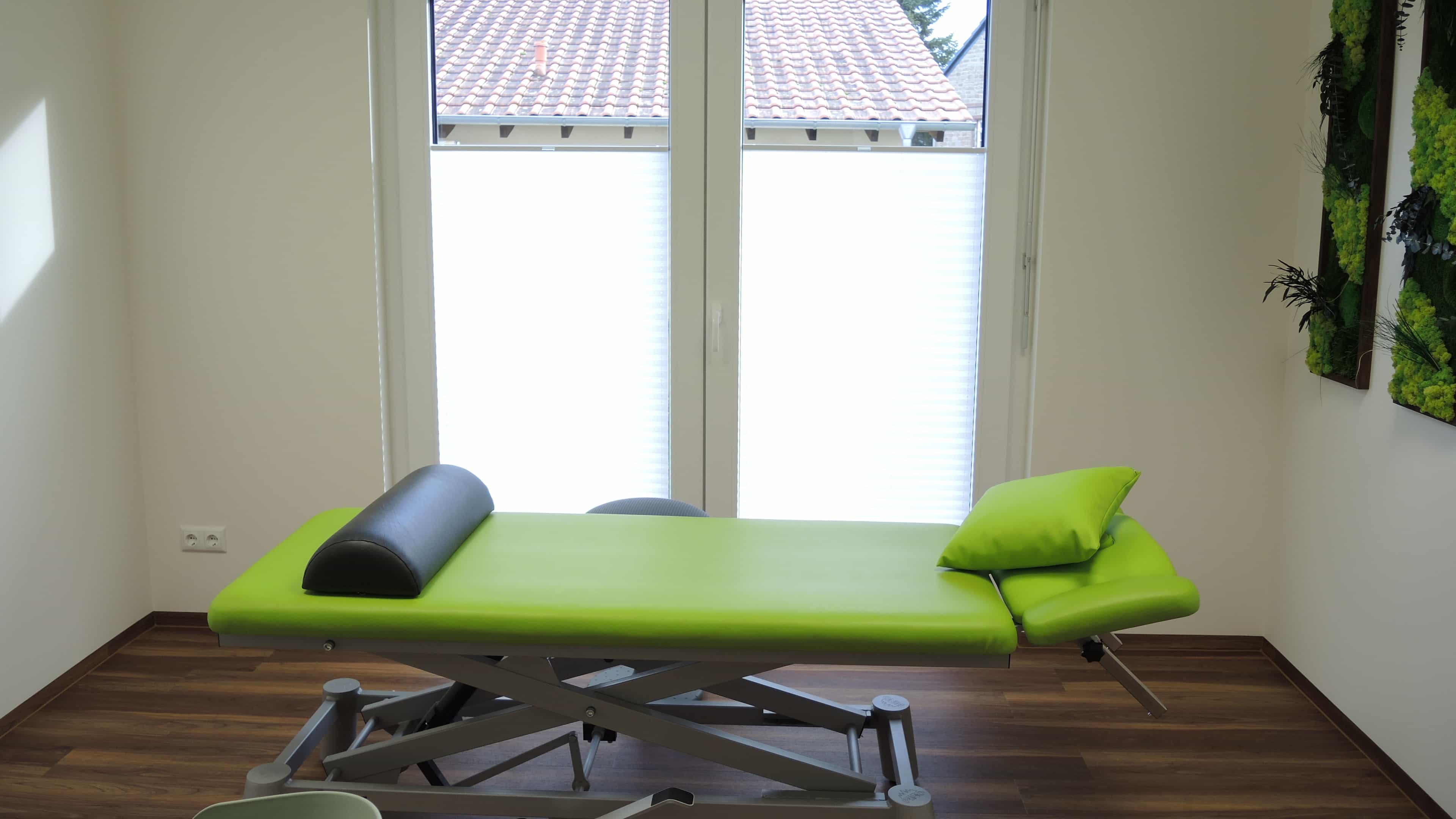 Behandlungsraum der Physiotherapiepraxis Ellrich mit grüner Liege und Fenster