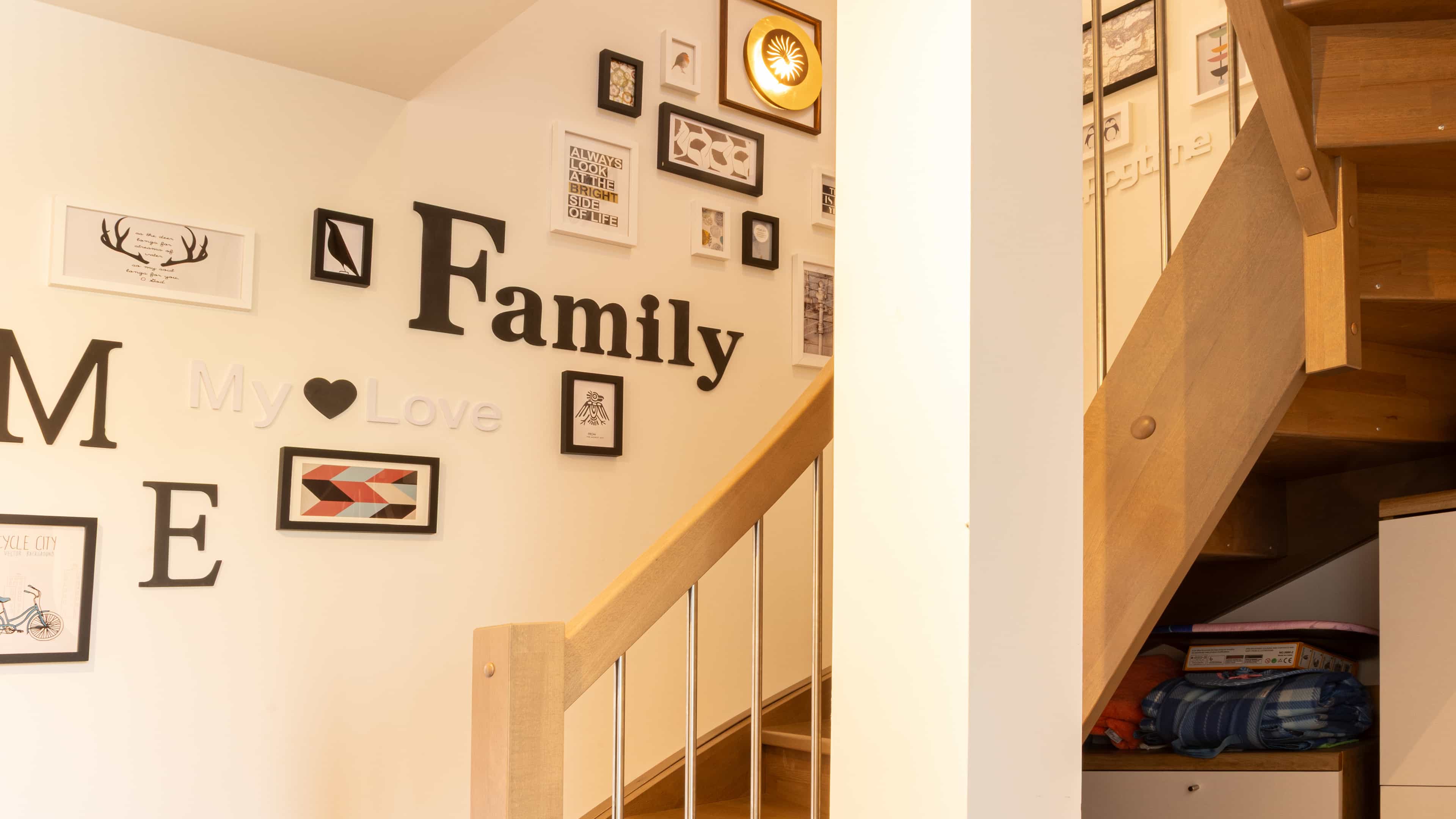 Flur mit Holztreppe und Wanddekoration mit Family-Schriftzug im Familienhaus Lampl von Haas