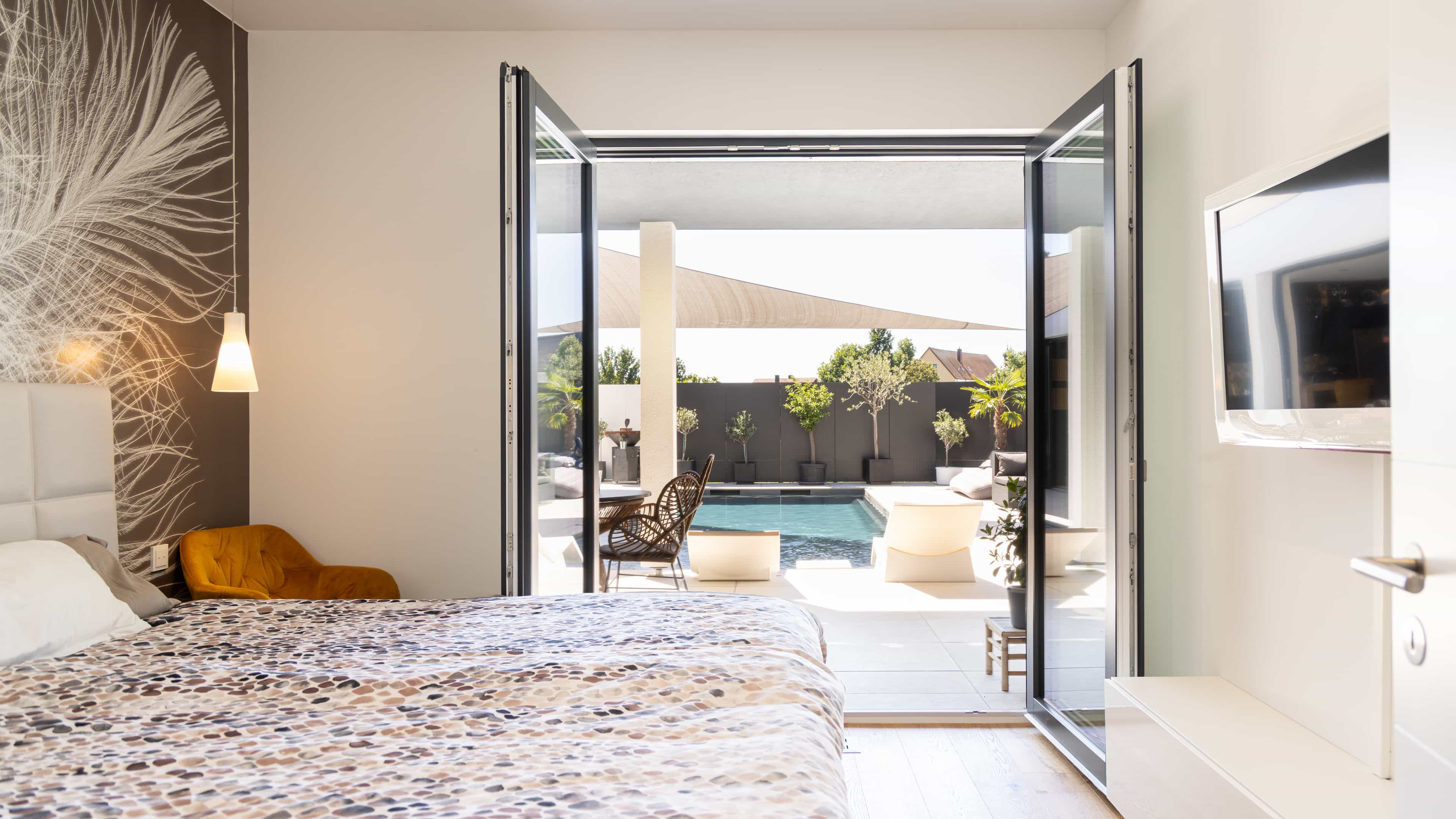 Schlafzimmer mit geöffneter Terrassentür und Blick auf den Pool im Familienhaus Eder von Haas