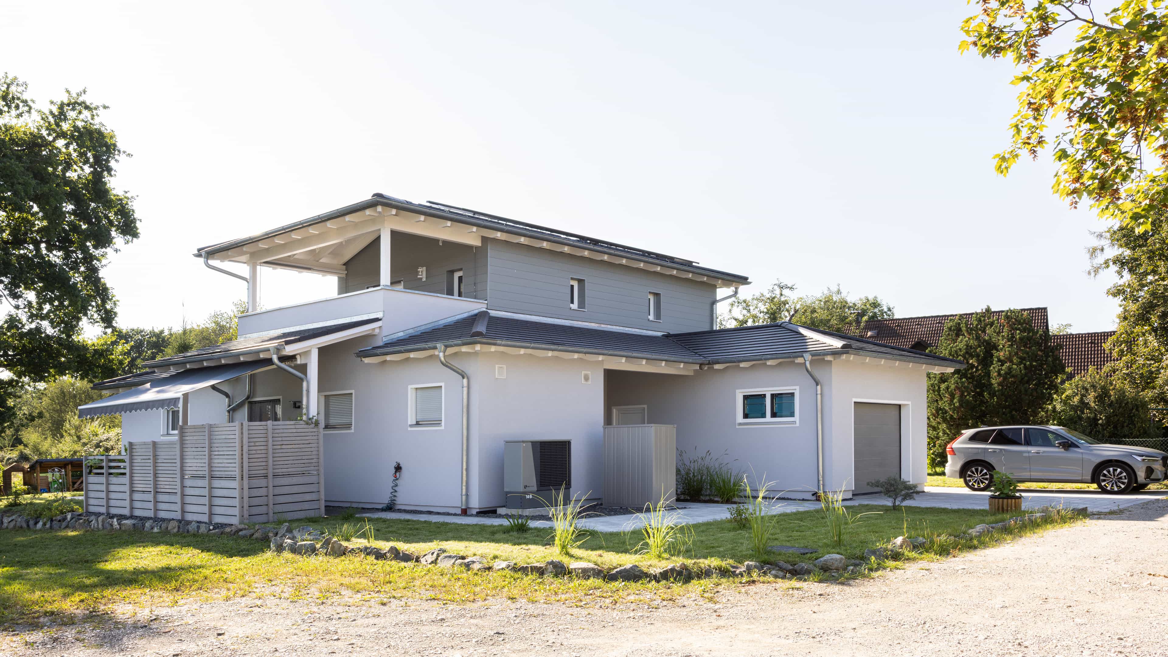 Straßenansicht des Familienhauses Lampl mit Staffelgeschoss, Balkon und Garage, Haas Fertighaus