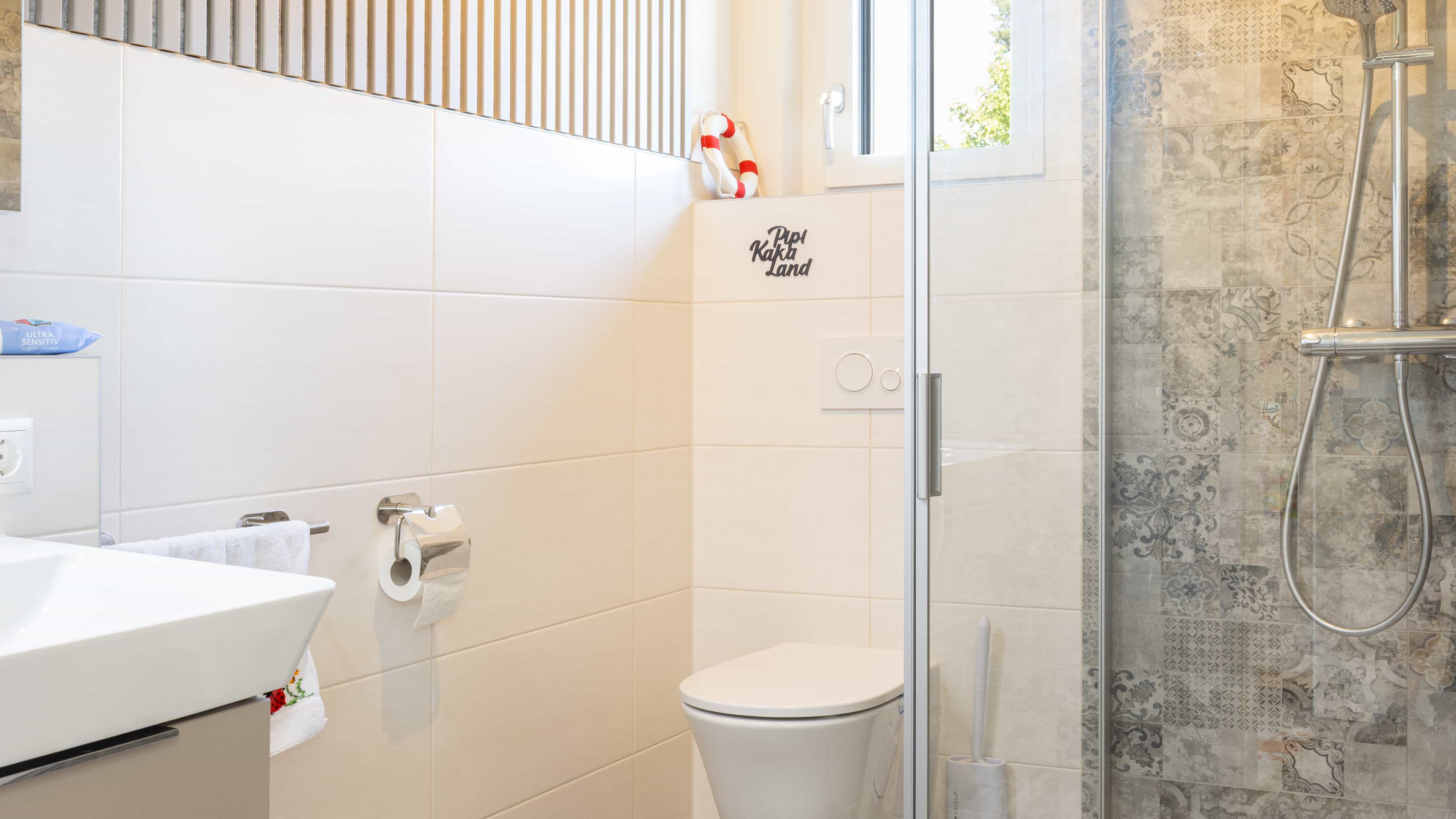 Badezimmer mit ebenerdiger Dusche und gemusterten Fliesen im Familienhaus Lampl von Haas