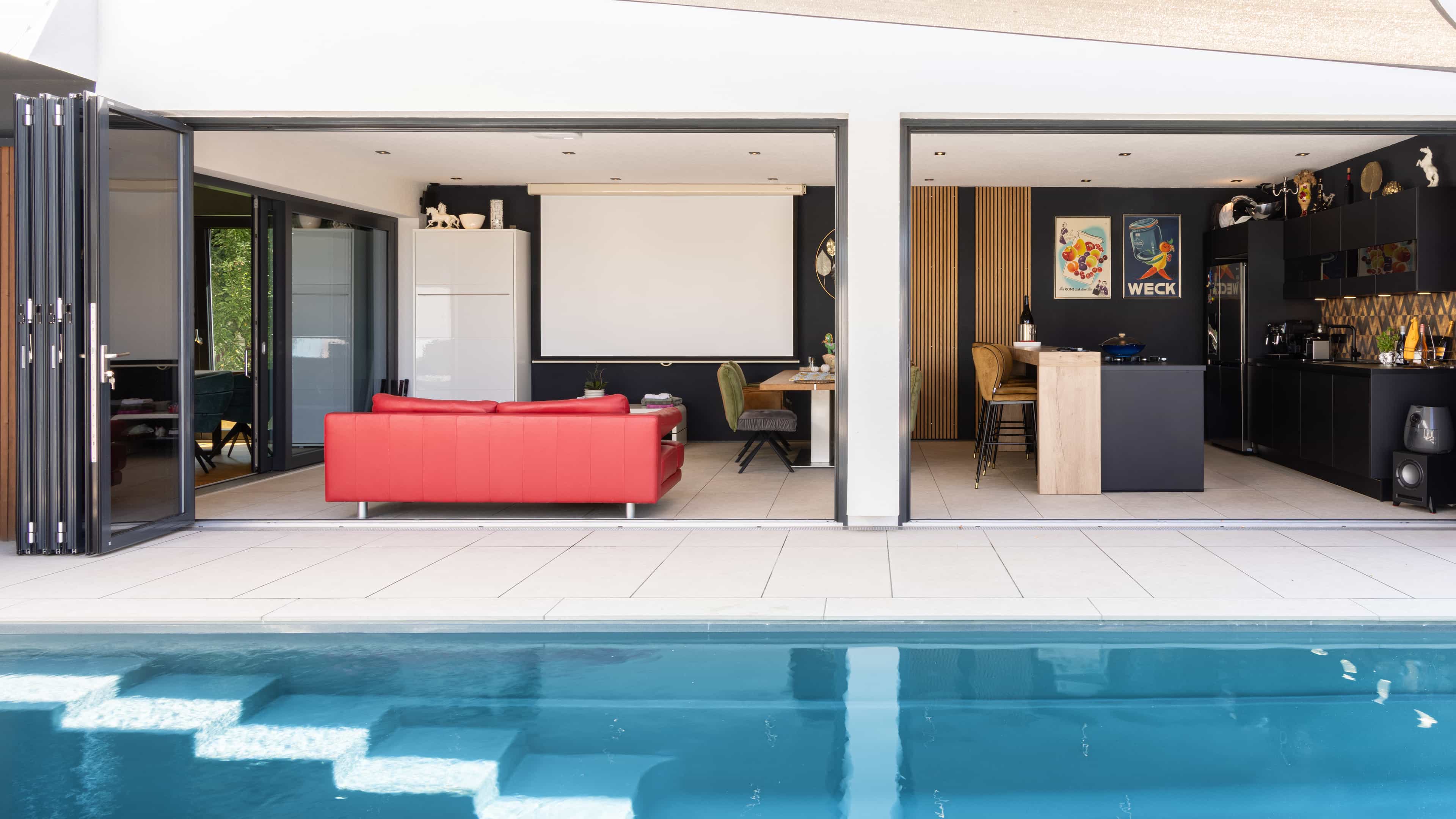 Pool mit Treppenstufen und Blick durch die Faltschiebetür in den Wohnraum des Familienhauses Eder