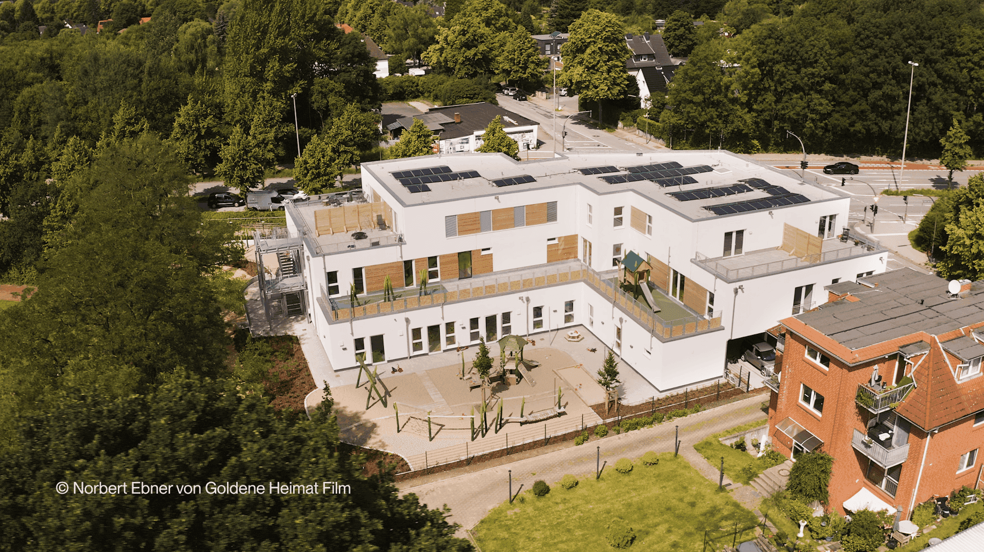 Luftaufnahme der Kita KD1 von Haas Gewerbebau mit Photovoltaik auf dem Flachdach und Spielplatz