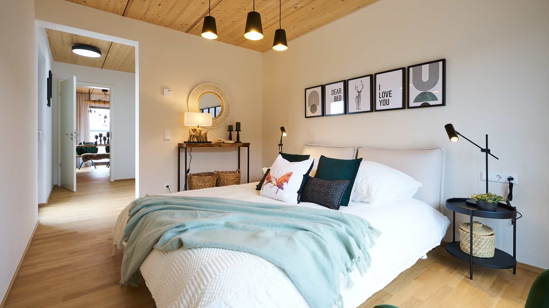 Schlafzimmer im Haas Fertighaus Verde S 140 mit sichtbarer Holzdecke und hellem Doppelbett