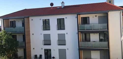 Mehrfamilienhaus in Wald mit rotem Ziegeldach und Balkonen, Außenansicht Dach-Wand-Decken-Konstruktion