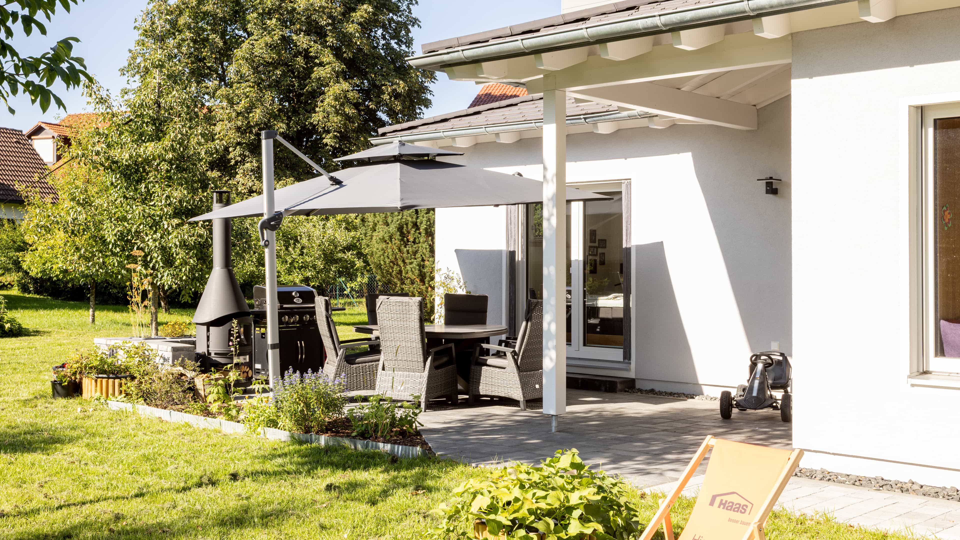 Terrasse mit Sonnenschirm, Essgruppe und Gartenblick am Familienhaus Lampl von Haas