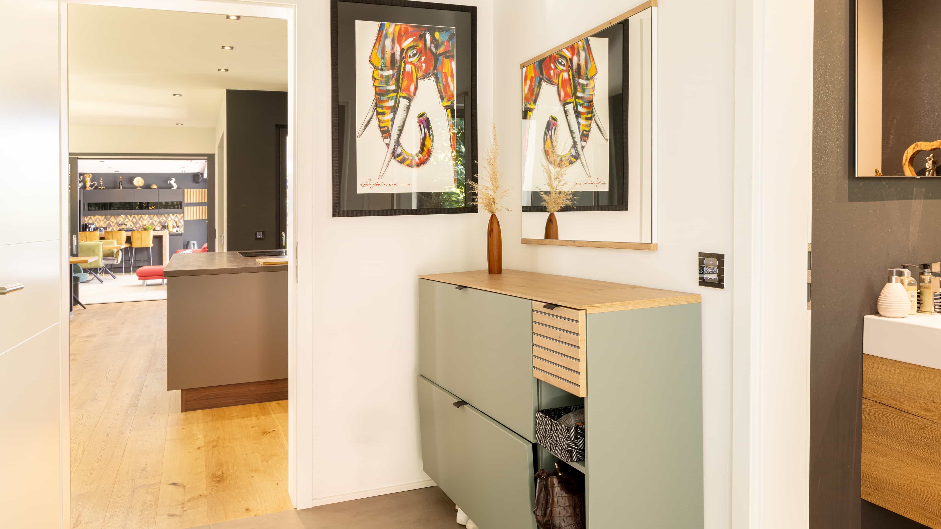 Flur im Bungalow der Familie Eder mit Sideboard, Elefanten-Bildern und Blick in den offenen Wohnbereich