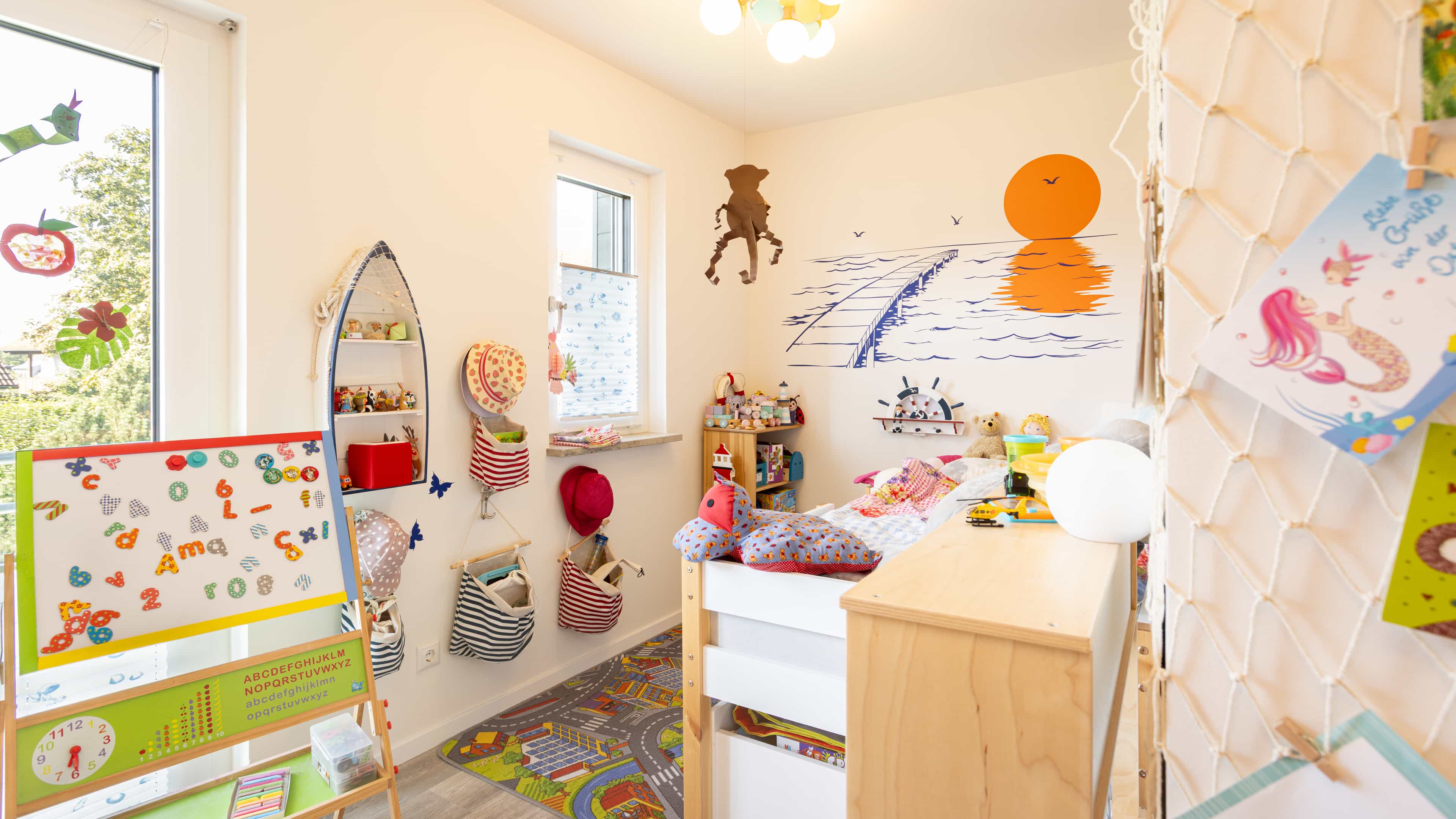 Kinderzimmer mit Wandmalereien, Spielzeug und Kletternetz im Familienhaus Lampl von Haas