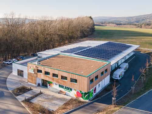 Luftaufnahme des Verkaufs- und Lagergebäudes der Ökokiste DonauWald mit Photovoltaik am Waldrand