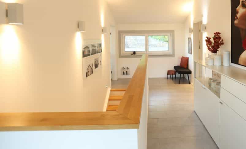 Flur mit Treppenabgang und Sideboard im Musterhaus Bad Vilbel, preisgekröntes Plusenergiehaus von Haas