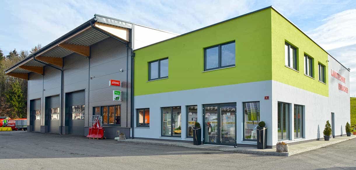 Bürogebäude von Landtechnik Embacher in Tirol mit grüner Fassade, Verkaufsbereich und Werkstatthalle