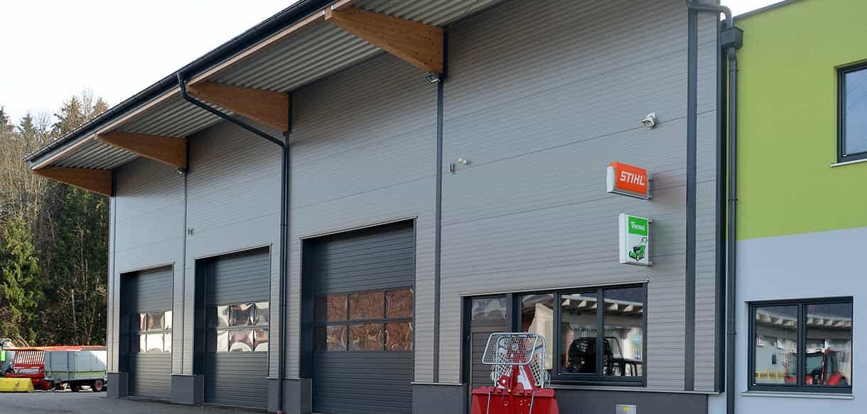 Werkstatthalle von Landtechnik Embacher mit Sektionaltoren, Vordach und grünem Bürotrakt