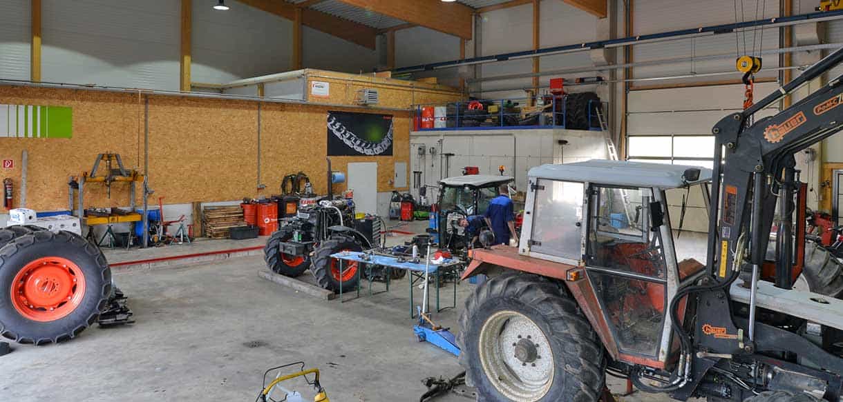 Werkstatt von Landtechnik Embacher mit Traktoren unter Holzdach