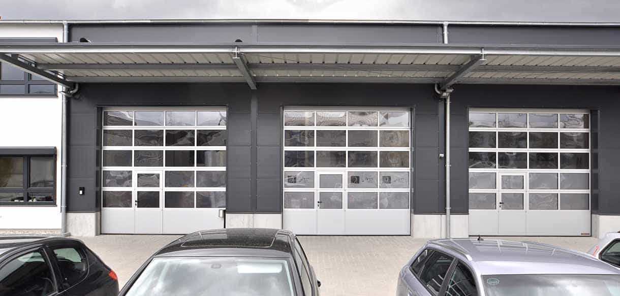 Hallentore mit Überdachung und parkenden Autos an der Lagerhalle der Felden GmbH