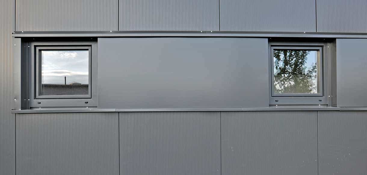Fassadendetail der Lagerhalle Jordan mit dunkler Metallverkleidung und Fenstern