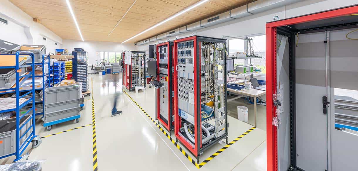 Produktionshalle der Dr. Eberl MBE-Komponenten GmbH innen mit Regalen, Anlagen und Holzdecke