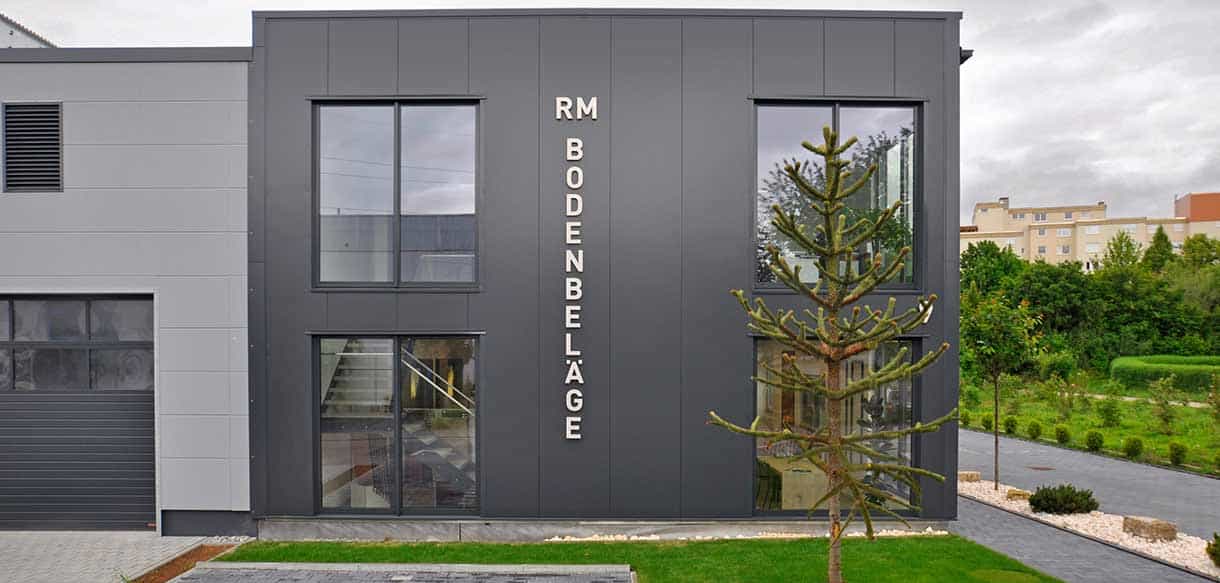 Fassade mit Schriftzug RM Bodenbeläge am Bürogebäude, dahinter die Lagerhalle, Haas Gewerbebau