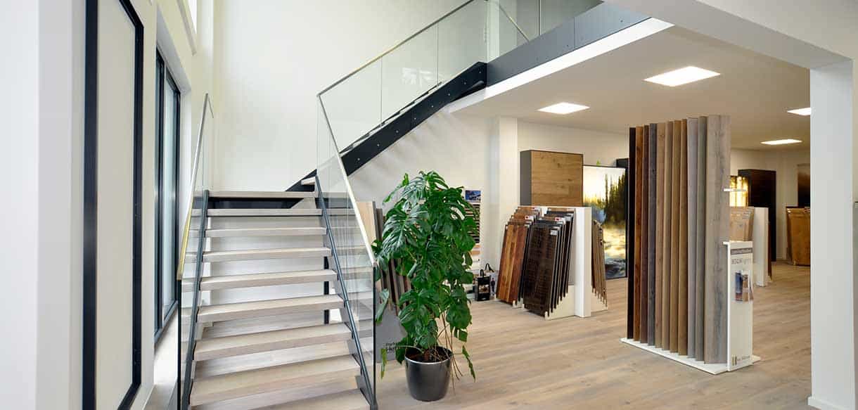 Treppe mit Glasgeländer und Bodenbelagsmustern in der Ausstellung von RM Bodenbeläge