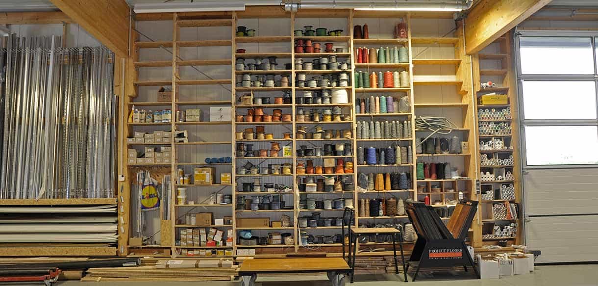 Lagerhalle von RM Bodenbeläge mit Regalen voller Teppichrollen, Farben und Profilen