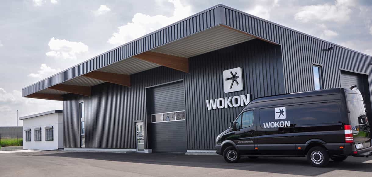 Bürogebäude mit Lager von Wokon mit dunkler Metallfassade, Vordach und Firmentransporter, Haas Gewerbebau