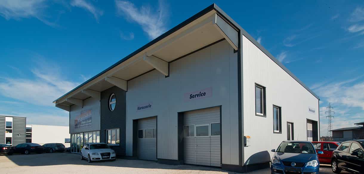 Werkstatt mit Ausstellungsraum und Büro von Autopark Windern mit weißer Fassade und Servicetoren