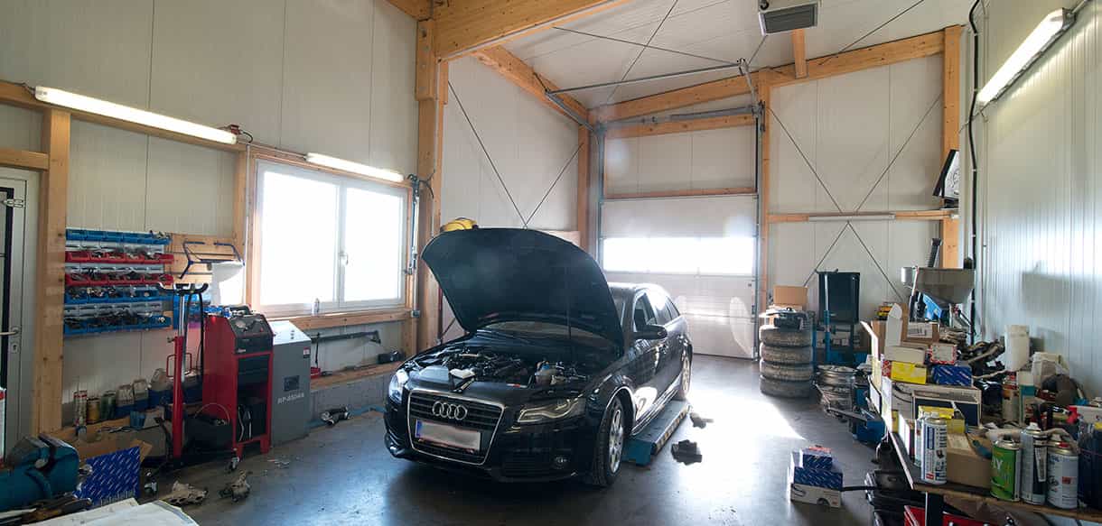 Werkstatthalle von Autopark Windern mit Holzdecke, Fahrzeug mit geöffneter Motorhaube und Werkzeug