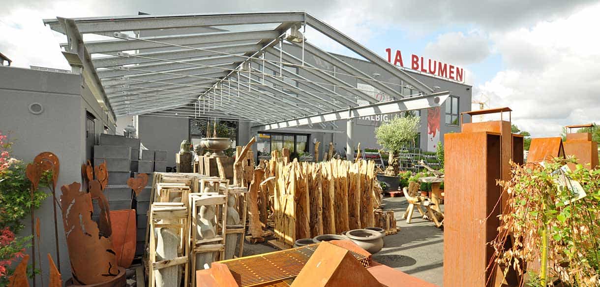 Überdachter Außenverkaufsbereich von 1A Blumen Halbig mit Gartendeko unter einer Glasdach-Konstruktion