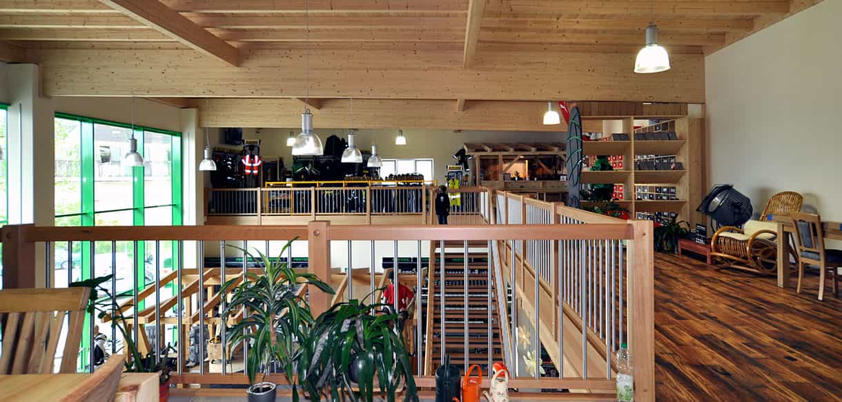 Verkaufsraum mit sichtbarer BSH-Decke und Holzgeländer der Galerie bei Endel & Dietze