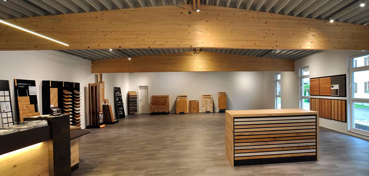 Ausstellungsraum des Holzfachhandels Plössl und Söhne mit Holzmustern, Tresen und Leimholzbinder