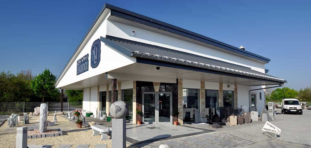 Ausstellungsgebäude von Naturstein Laubner in Pilsting mit Eingangsüberdachung und Steinausstellung im Freien