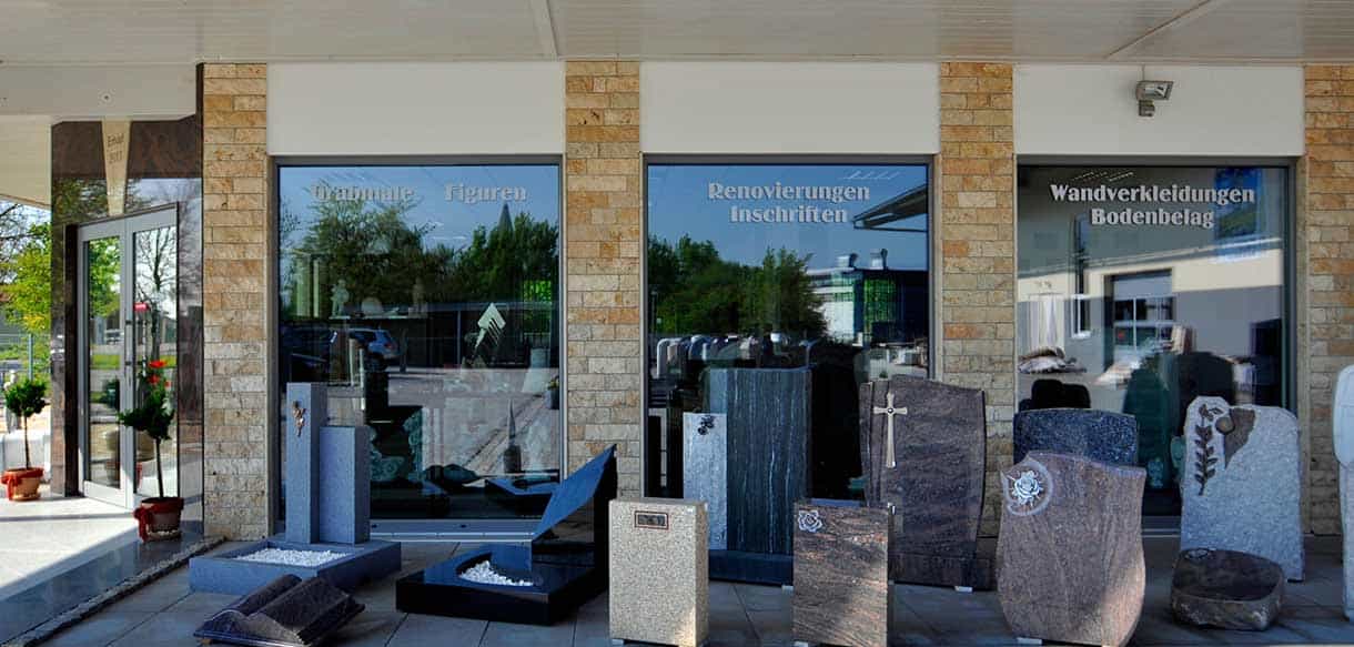 Schaufenster der Ausstellung von Naturstein Laubner mit Grabsteinen und Natursteinsäulen am Eingang
