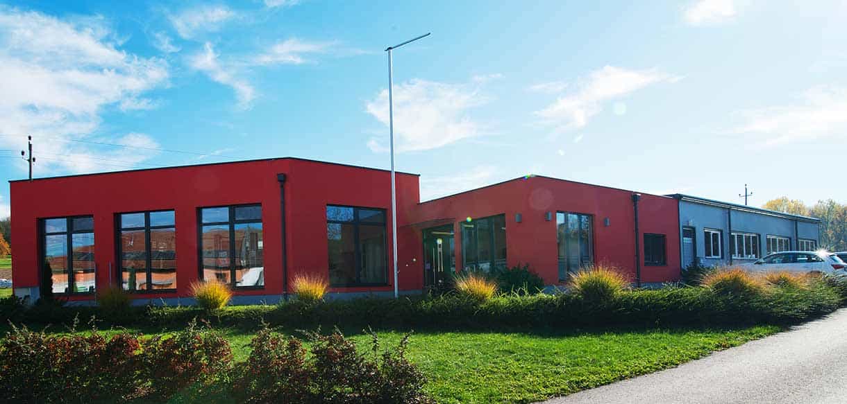 Straßenseitige Außenansicht der roten Gebäude mit Büro, Ausstellungsraum und Produktion von Vorhauer, Haas Gewerbebau