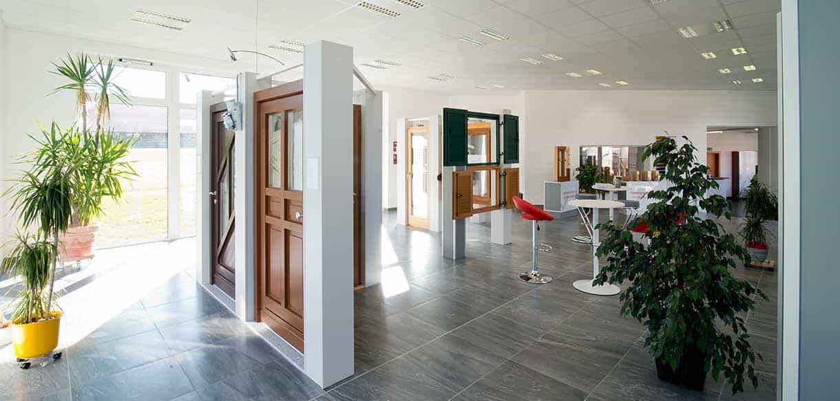 Showroom von Vorhauer mit Musterhaustüren aus Holz, Grünpflanzen und Stehtischen im hellen Ausstellungsraum