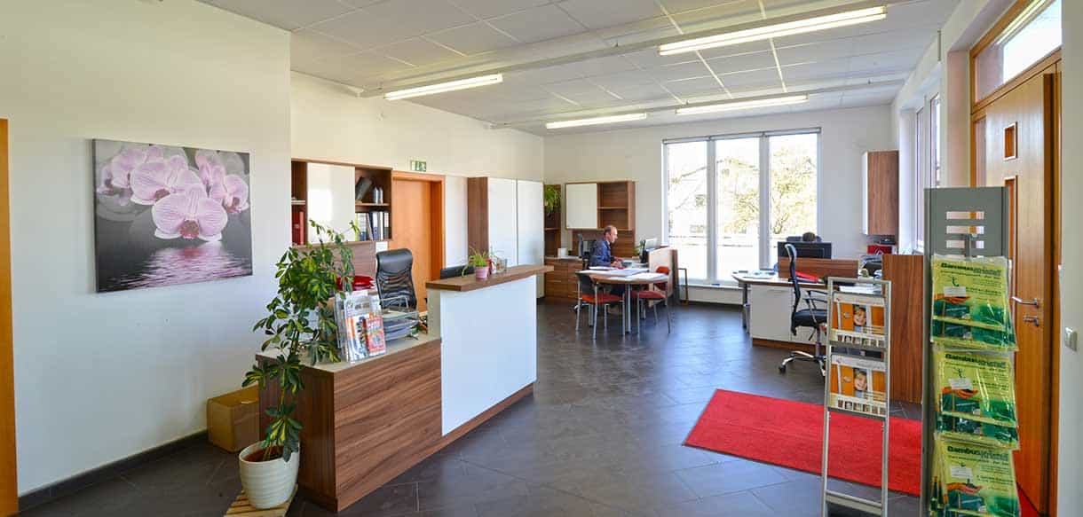 Empfangstresen mit Pflanzen und rotem Teppich im Büro- und Ausstellungsgebäude von Vorhauer, Haas Gewerbebau