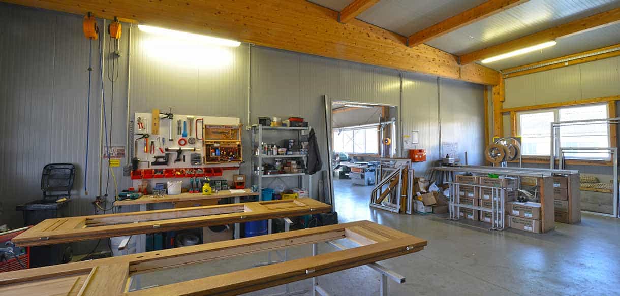 Werkstatt mit Werkbänken, Werkzeugwand und Holzdachbindern in der Produktionshalle von Vorhauer, Haas Gewerbebau
