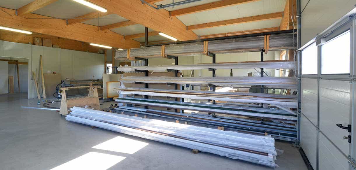 Lagerbereich der Produktionshalle von Vorhauer mit Profilregalen, offenem Sektionaltor und Holzdachkonstruktion
