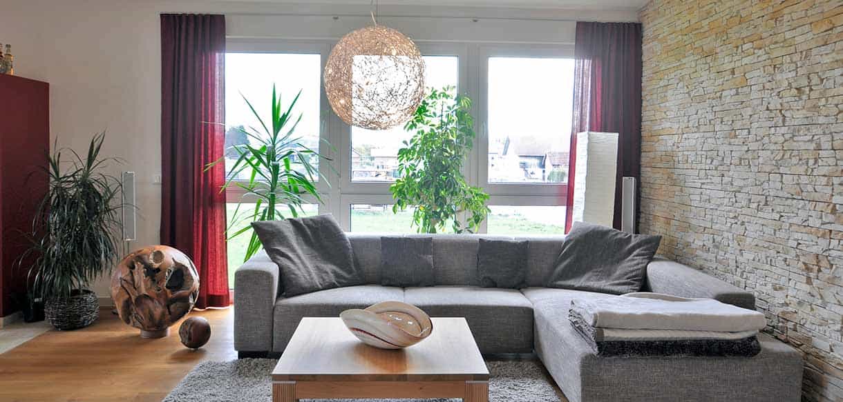Wohnzimmer der Wohnung im Betriebsgebäude des Ofenhaus Weindl in Mitterskirchen mit Ecksofa und Natursteinwand