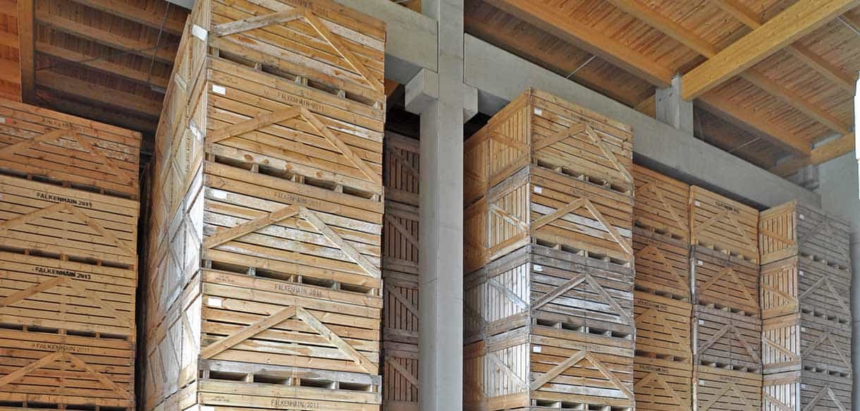 Gestapelte Kartoffelkisten unter dem Holzdach der Lagerhalle Falkenhain