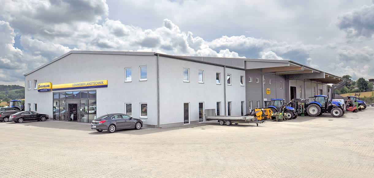 Werkstattgebäude von Leinweber Landtechnik in Neuhofen mit Landmaschinen unter Wolkenhimmel