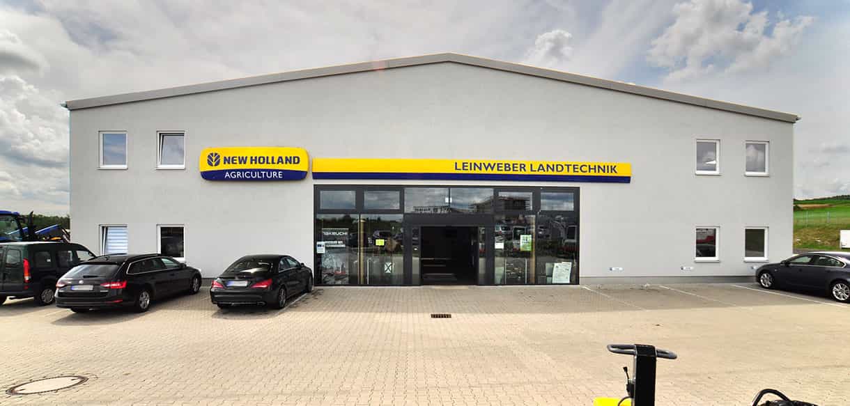 Eingangsseite von Leinweber Landtechnik in Neuhofen mit Schild und Parkplatz