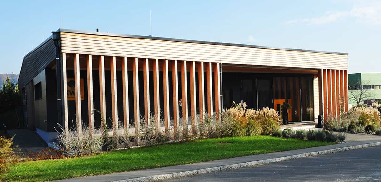 Ausstellungsgebäude von KWB mit Holzlamellenfassade und überdachtem Eingang von Haas Gewerbebau