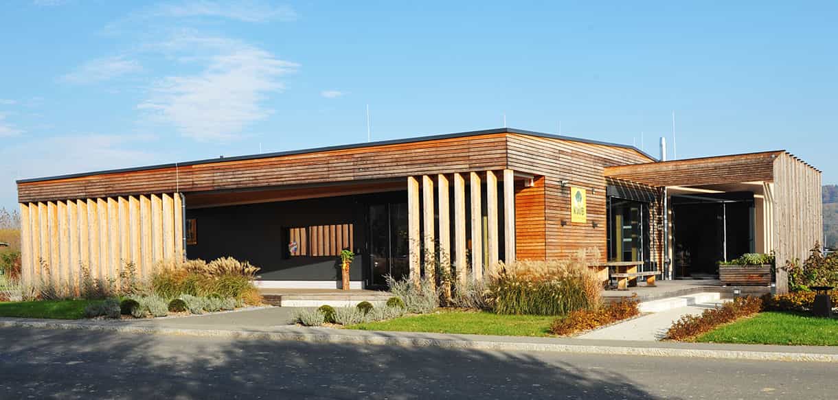 Ausstellungsgebäude KWB mit Holzfassade, Lamellen und Ziergräsern vor dem Eingang