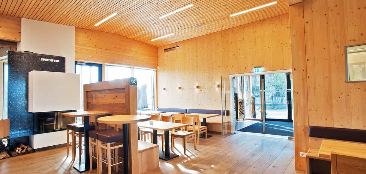 Veranstaltungsraum im KWB-Gebäude mit Holzdecke, Tischen und Kaminofen