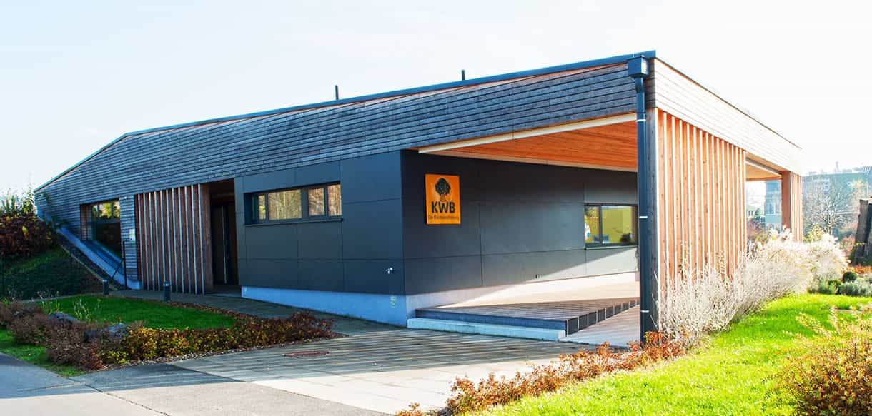 Rückansicht des KWB-Gebäudes mit dunkler Fassade, Holzlamellen und überdachter Terrasse