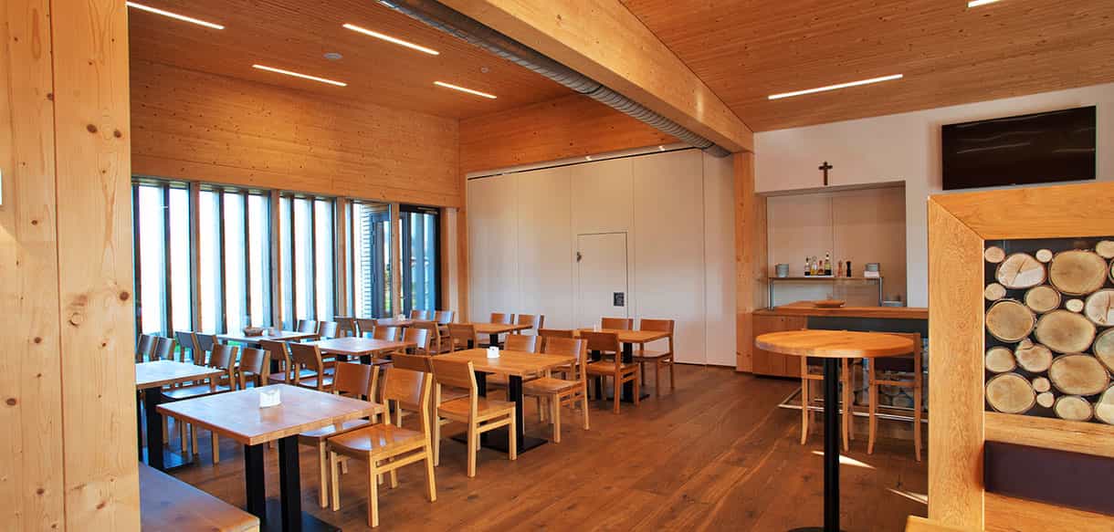 Veranstaltungsraum mit Holzdecke, Tischen und Fensterband im KWB-Ausstellungsgebäude