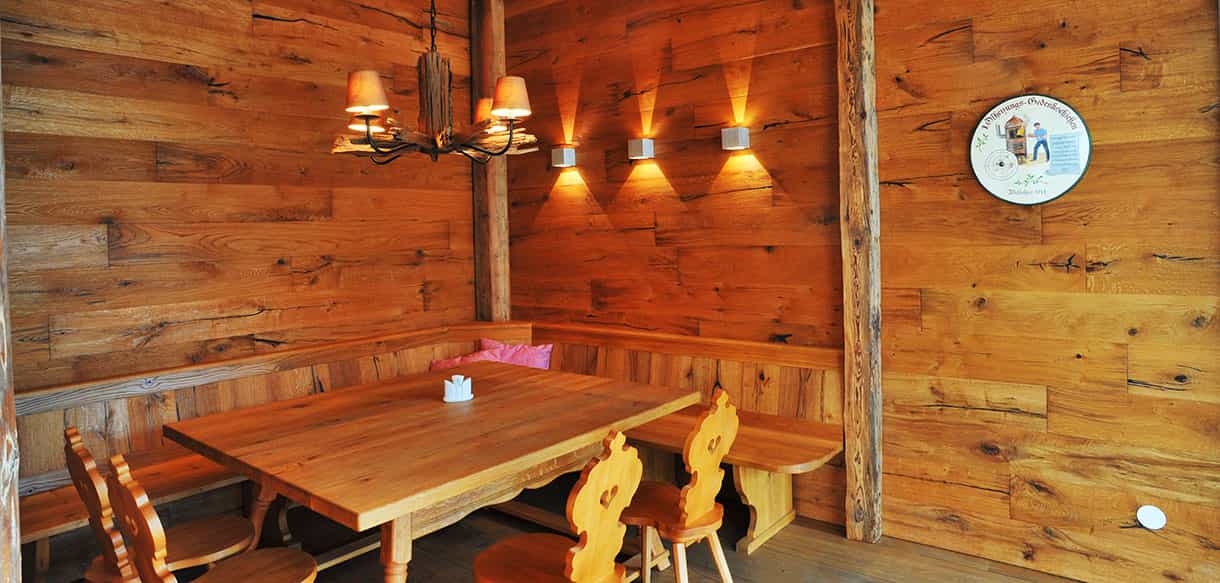 Stube mit Altholzwand, Eckbank und langem Holztisch im KWB-Ausstellungsgebäude